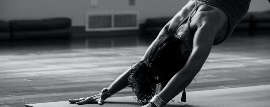 Health and fitness: A black and white photo of a person doing down facing dog on a yoga mat