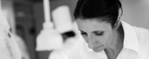 A black & white photo of Anne-Sophie Pic plating up using tweezers